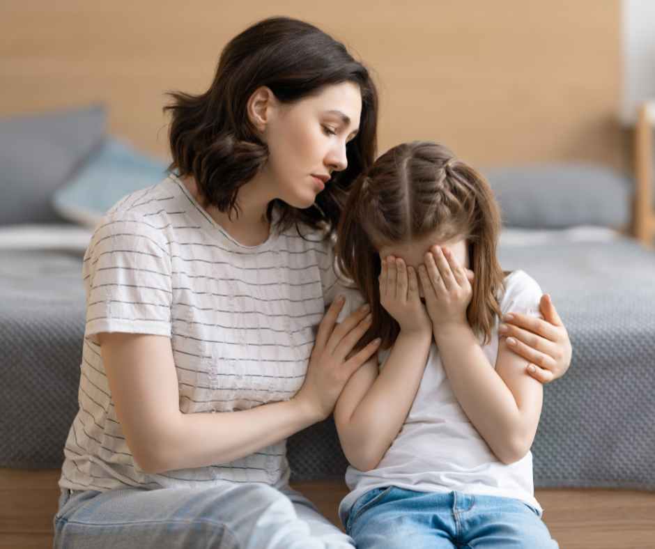 Mother calmly supporting her child during a tantrum at home—showcasing emotional regulation during kids' meltdowns