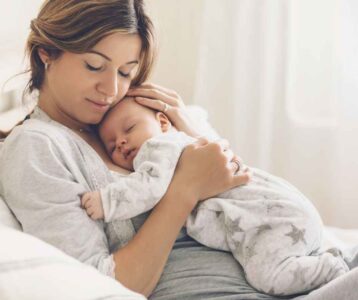 A new mom gently holding her baby while resting in bed after a cesarean section, focusing on healing and recovery.