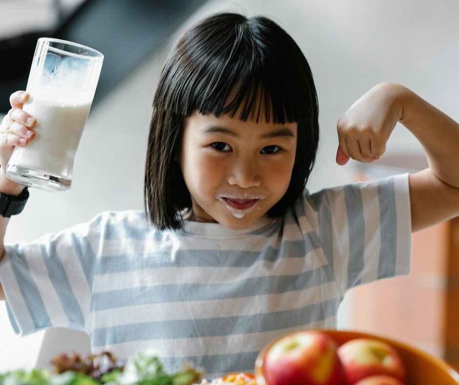 Toddler sitting at a table with three cups labeled milk, water, and juice—learning Healthy Beverage For Your Child.