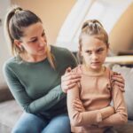 A calm mother kneeling at eye level, talking patiently to her upset child – Parenting with Patience in action.