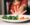A smiling Picky Eater picking colorful vegetables off a plate shaped like a happy face, with a mom encouraging gently nearby.