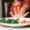 A smiling Picky Eater picking colorful vegetables off a plate shaped like a happy face, with a mom encouraging gently nearby.