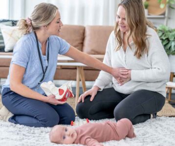 A Postpartum Body Changes, mom gently touching her belly while holding her newborn, reflecting on the changes her body has gone through.