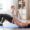 A mom sitting on a yoga mat practicing gentle pelvic floor exercises at home.