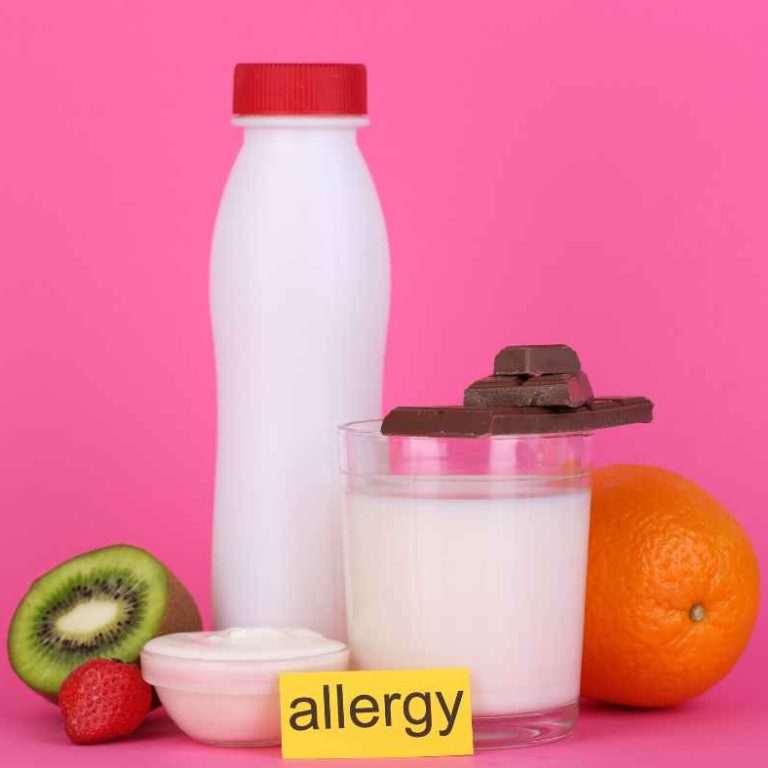 Parent feeding their baby a small spoonful of peanut butter in a highchair to introduce allergenic foods safely.