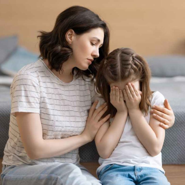 Mother calmly supporting her child during a tantrum at home—showcasing emotional regulation during kids' meltdowns