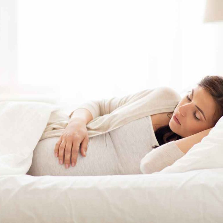 Pregnant woman sleeping on her left side with a pregnancy pillow—demonstrating safe and comfortable pregnancy sleep positions