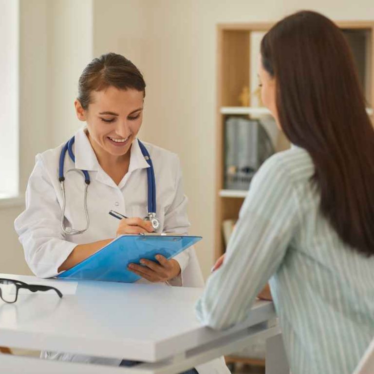 A mom smiling during a routine doctor visit, highlighting the importance of regular checkups for moms.